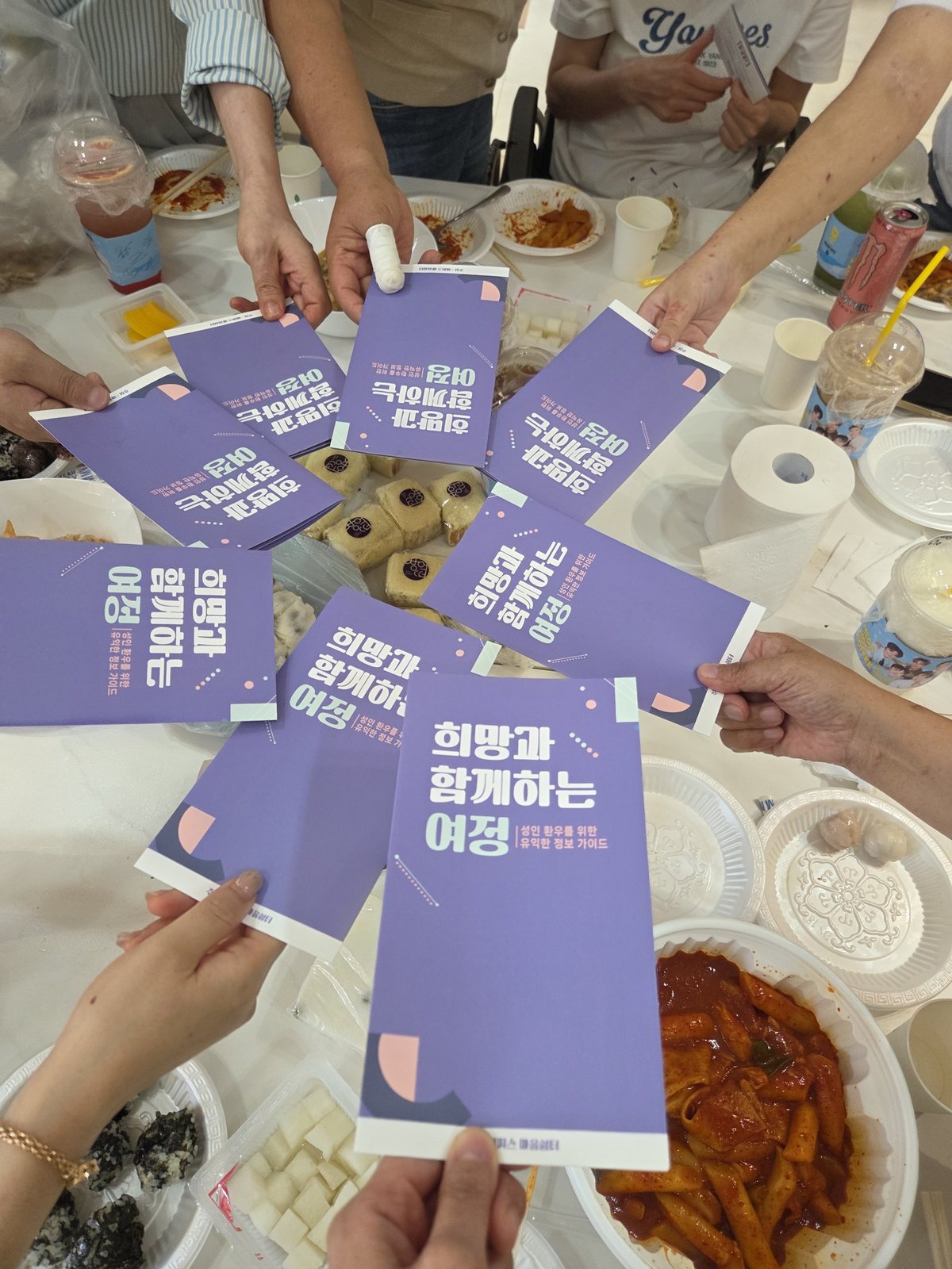 참가자들이 성인 환우를 위한 정보 가이드 '희망과 함께하는 여정' 책자를 손에 들고 둥글게 모아 든 모습