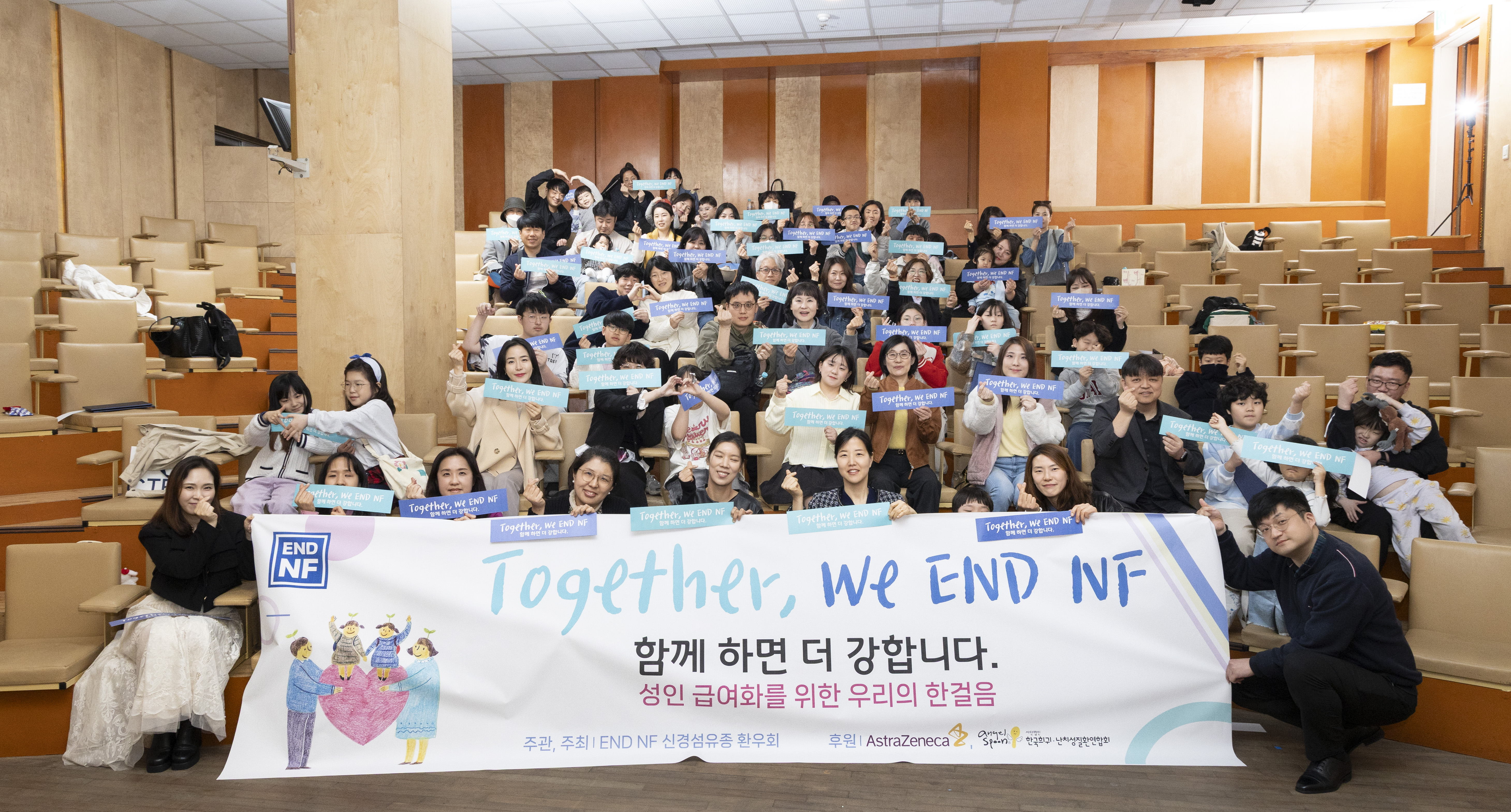 2026년 3월 28일 서울 용산구 이태원에서 열린 END NF 봄 세미나 단체 사진. 'Together, We END NF — 함께 하면 더 강합니다, 성인 급여화를 위한 우리의 한걸음' 현수막 앞에서 환우와 가족이 함께 포즈를 취하고 있다.